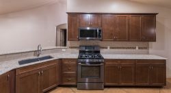 Kitchen cabinets with sink, stainless stove, and microwave hood fan.